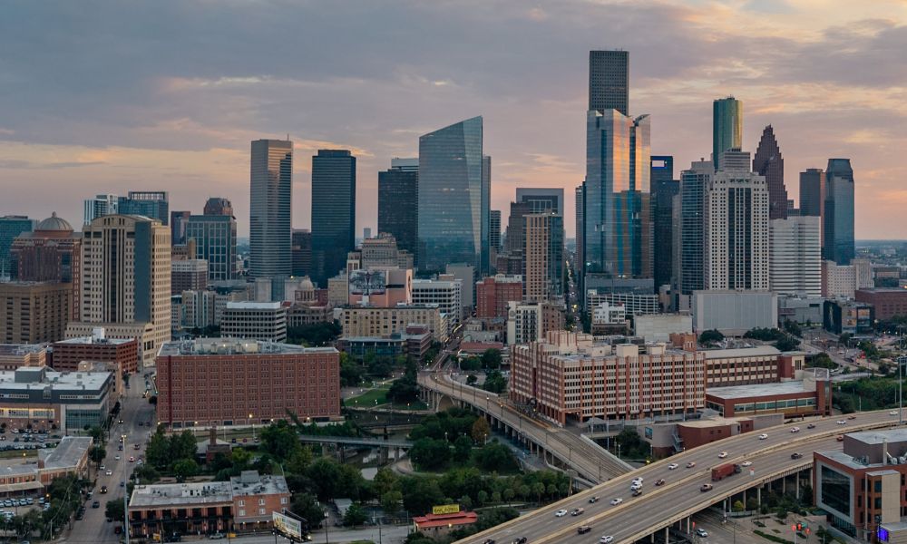 Houston skyline at sunset, featuring skyscrapers and busy highway. Urban cityscape view with colorful evening sky.