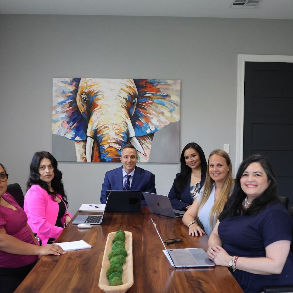 Business meeting with diverse professionals in modern conference room, colorful elephant painting in background.
