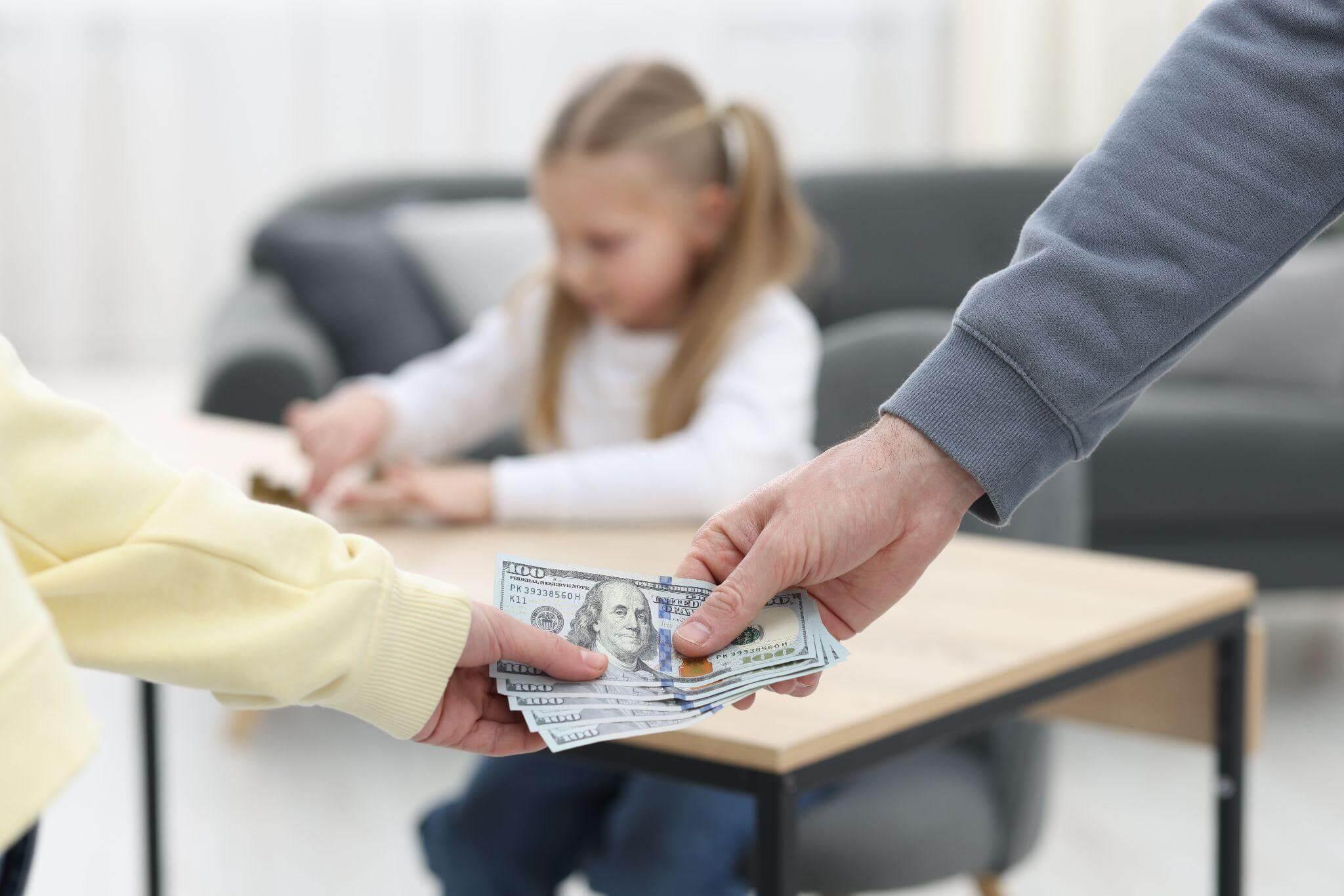 Adult handing child support money to a child