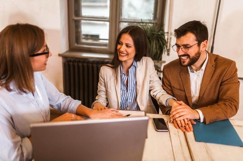A group of people sitting around a laptop
